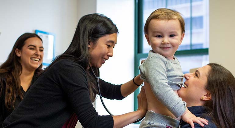 Image of mother holding toddler while doctor examines him